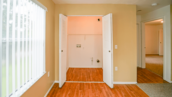Washer and dryer connections with a large window and vertical blinds.